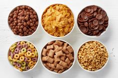 six bowls filled with different types of cereals and other food items on a white surface