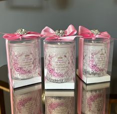 three glass jars with pink bows on them are sitting on a table next to each other