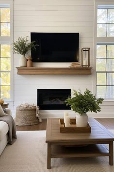 a living room with a couch, coffee table and television mounted on the wall above it