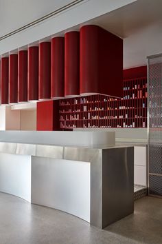 an empty room with red and white columns on the wall next to a metal counter