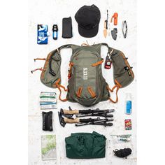 the contents of a backpack laid out on a white surface, including fishing gear and other items