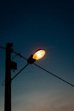 a street light is lit up against the evening sky with clouds in the back ground