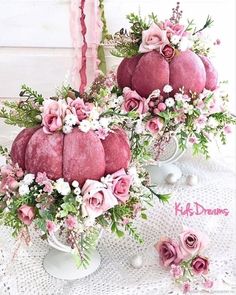 two vases filled with pink flowers on top of a white cloth covered tablecloth