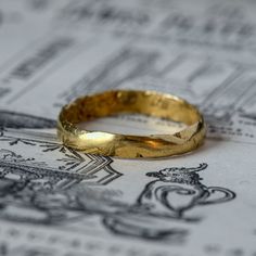 two gold wedding bands sitting on top of a piece of paper