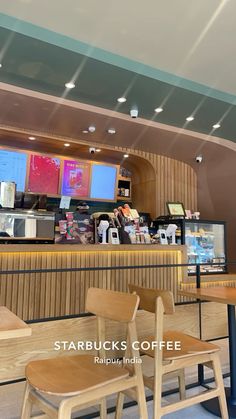 two wooden chairs sitting in front of a counter with menus on the wall behind them