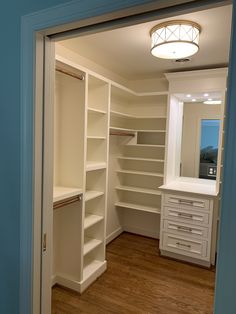 an empty walk - in closet with white shelves and drawers on the door way to another room