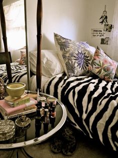 a bedroom with zebra print bedding, pillows and accessories on a table in front of a mirror