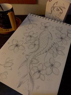 a drawing of a koi fish and flowers on a desk next to a coffee mug