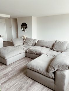 a large sectional couch sitting on top of a hard wood floor in a living room