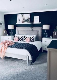 a bedroom decorated in black and white with pops of pink on the bed, nightstands