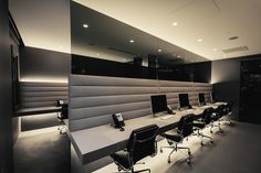 an empty conference room with black chairs and white desks, along with lights on the ceiling