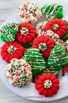 red, green and white decorated cookies on a white plate with sprinkles