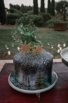 a decorated cake sitting on top of a wooden table next to a plate with candles