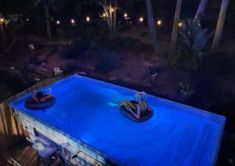 an aerial view of a pool at night with two people on inflatable rafts