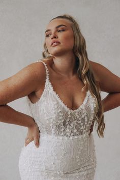 a woman wearing a wedding dress with an open back and spaghetti straps, posing for the camera