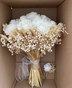 a bouquet of white roses in a cardboard box with some ribbon on the side and a bow tied around it