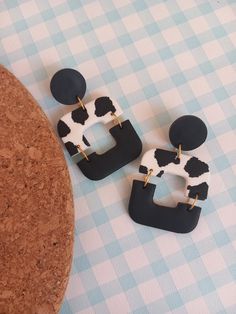 two black and white earrings sitting on top of a blue checkered cloth tablecloth