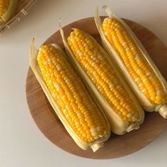 three ears of corn on a wooden plate