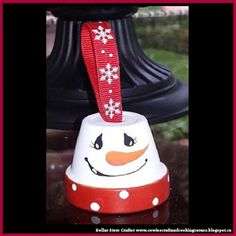 a snowman bell with a red ribbon hanging from it's top on a table