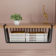 a shelf with books and a potted plant sitting on top of it next to a gold giraffe figurine