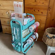 a blue cart filled with lots of crafting supplies next to a dresser and drawers