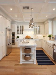 a kitchen with white cabinets and an island in the middle, along with a blue rug on the floor