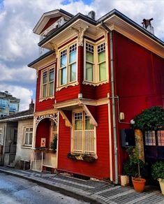 a red house with white balconies on the roof and windows, in an urban setting