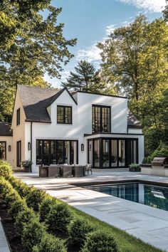 a large white house with black windows next to a pool