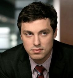 a man in a suit and tie looking at the camera with serious expression on his face