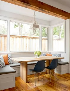 a dining room table and bench in front of a large window with wood flooring