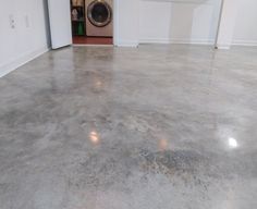 an empty room with a washer and dryer on the floor in front of it