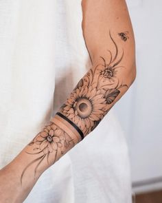 a woman's arm with sunflowers on it and a bee in the background