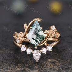 a green and white stone surrounded by leaves on top of a gold ring with diamonds