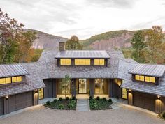 this is an aerial view of a house in the woods with mountains in the background