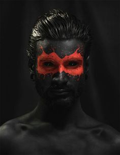 a man with black and red paint on his face is shown in front of a dark background