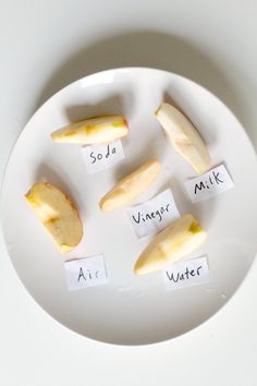 four pieces of fruit on a white plate with words written on them that spell out their names