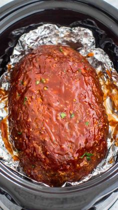 a slow cooker filled with meat covered in sauce