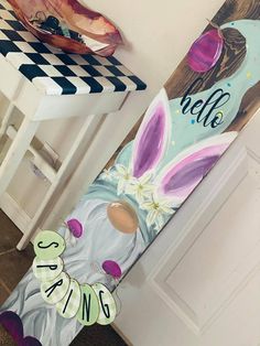 a wooden sign that says hello spring next to a white chair and table with an easter bunny painted on it