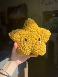 a person holding up a yellow star shaped object in their hand with eyes drawn on it