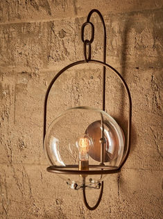 a light hanging from the side of a wall with a glass ball on it's end