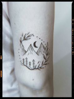 a person with a tattoo on their leg that has mountains and trees in the background