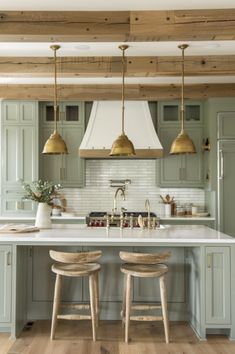 a kitchen with two stools in front of an island and three lights hanging from the ceiling