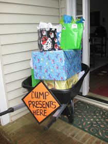 a wheelbarrow filled with boxes and bags on the front door steps, next to a sign that says dump presents here