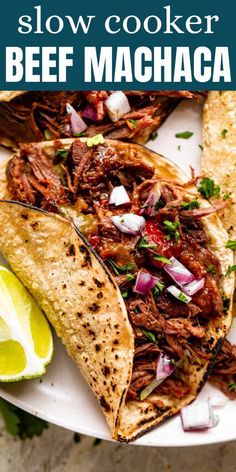 the slow cooker beef machaca is served on a plate with lime wedges