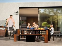 a family sitting around a table outside on the patio with their child's food