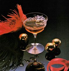 a cocktail glass with an orange garnish in it next to some other items