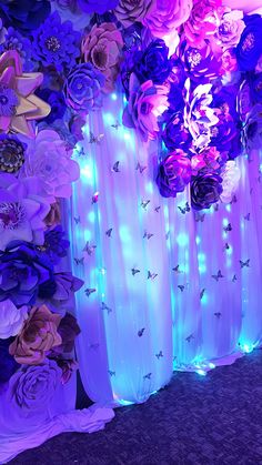 purple flowers and lights are on display in front of a backdrop that is made up of sheer curtains