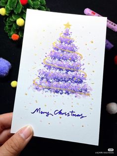 someone holding up a christmas card with a purple tree on it