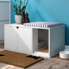 a white cabinet sitting on top of a wooden floor next to a potted plant