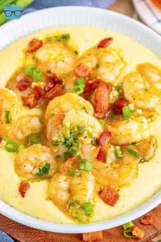 a white bowl filled with shrimp and grits on top of a wooden cutting board